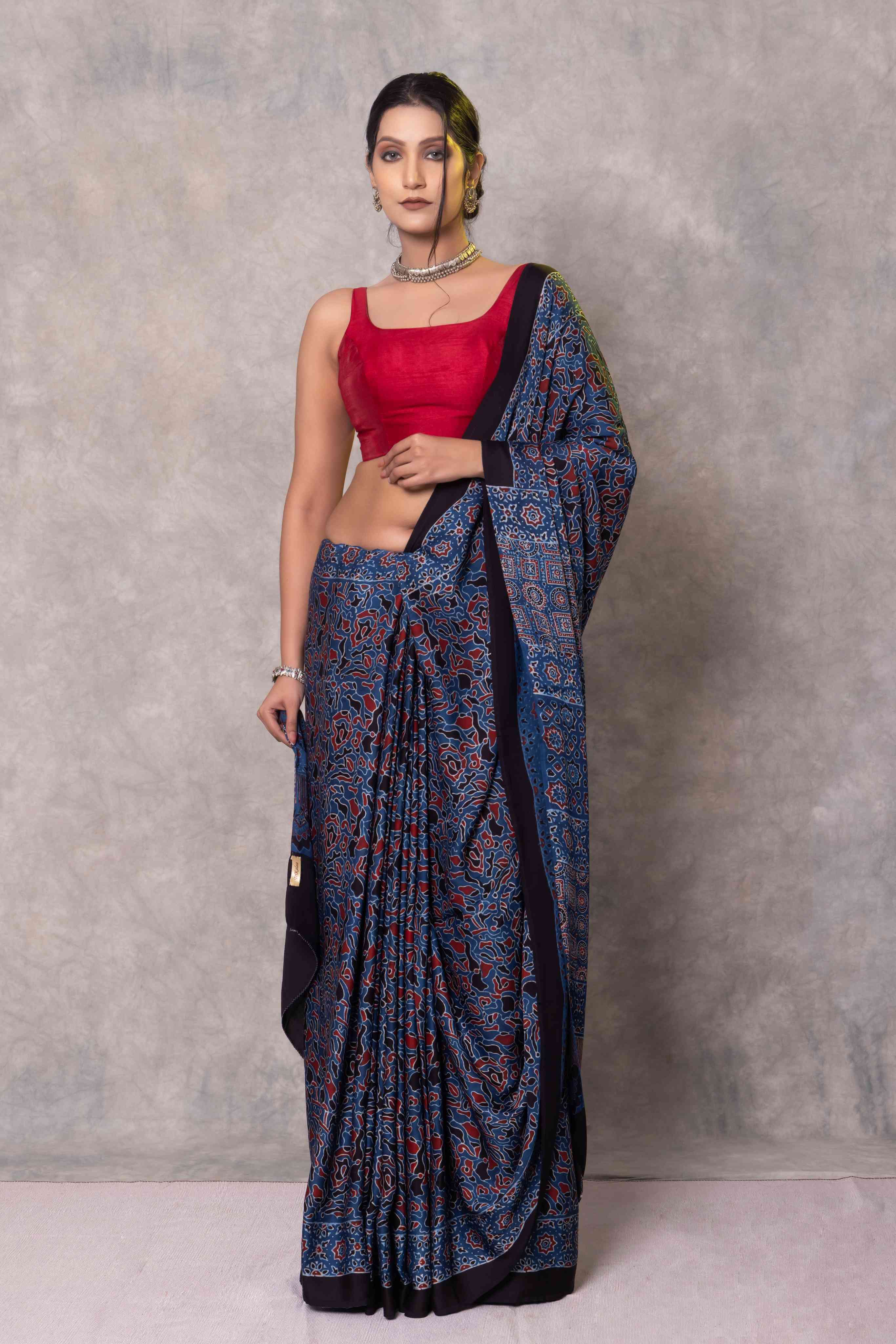 Woman wearing a blue saree with a red blouse against a gray background