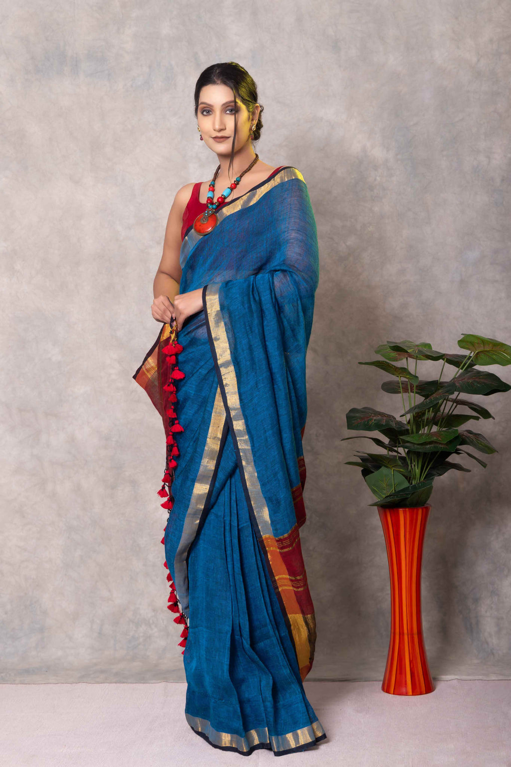 Woman in a blue saree with a plant on a gray background