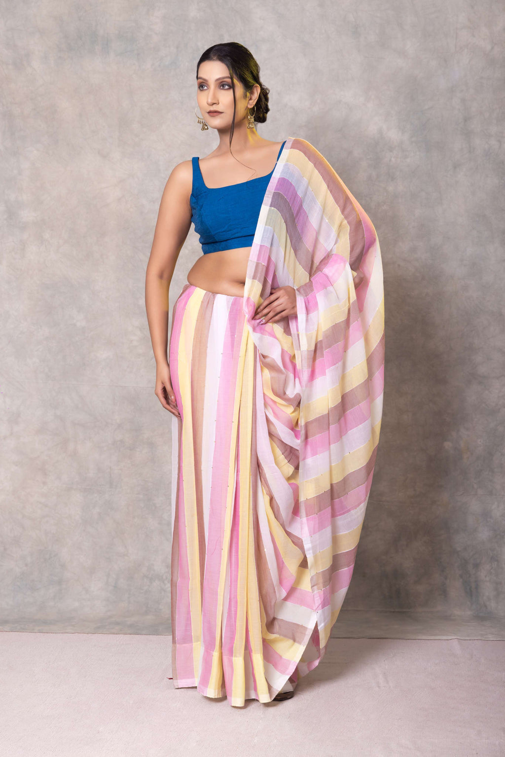 Woman wearing a colorful saree with a blue blouse against a gray background