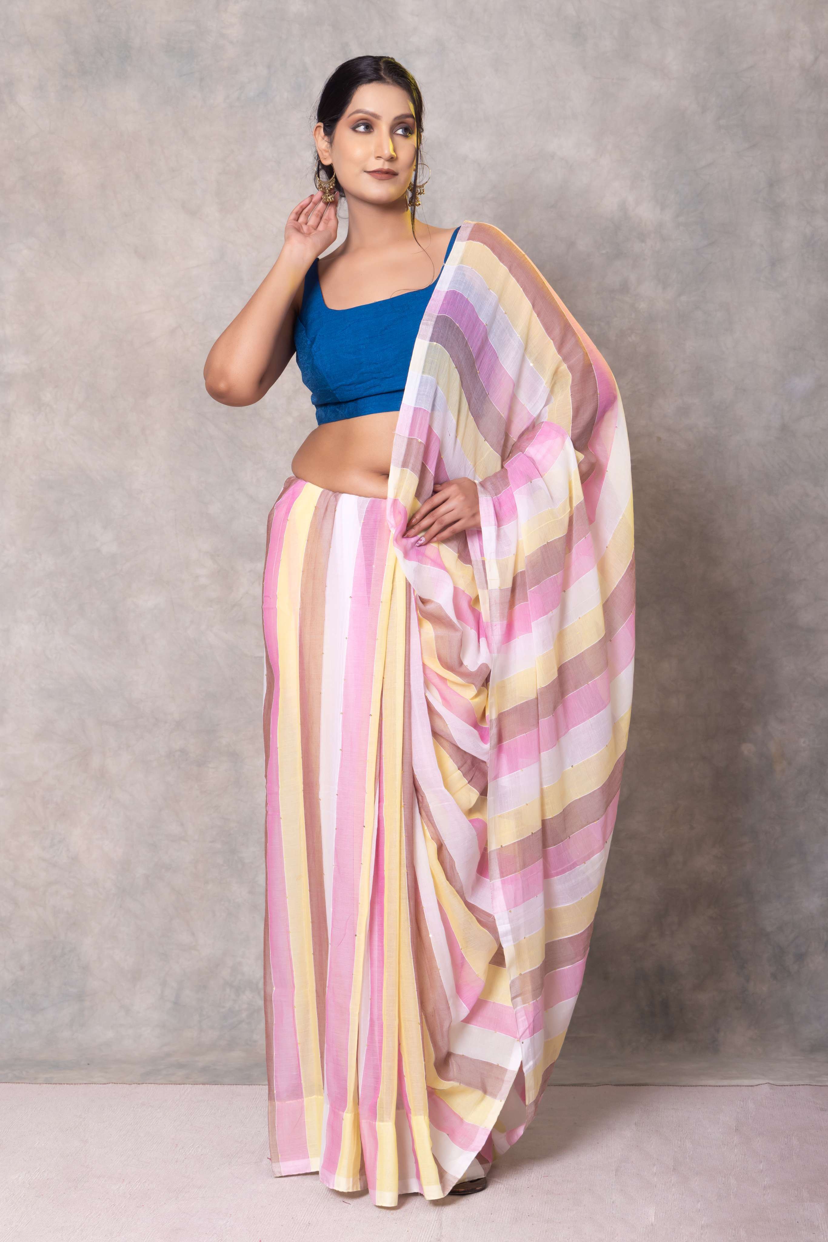 Woman wearing a blue blouse and pink and yellow striped saree against a gray background