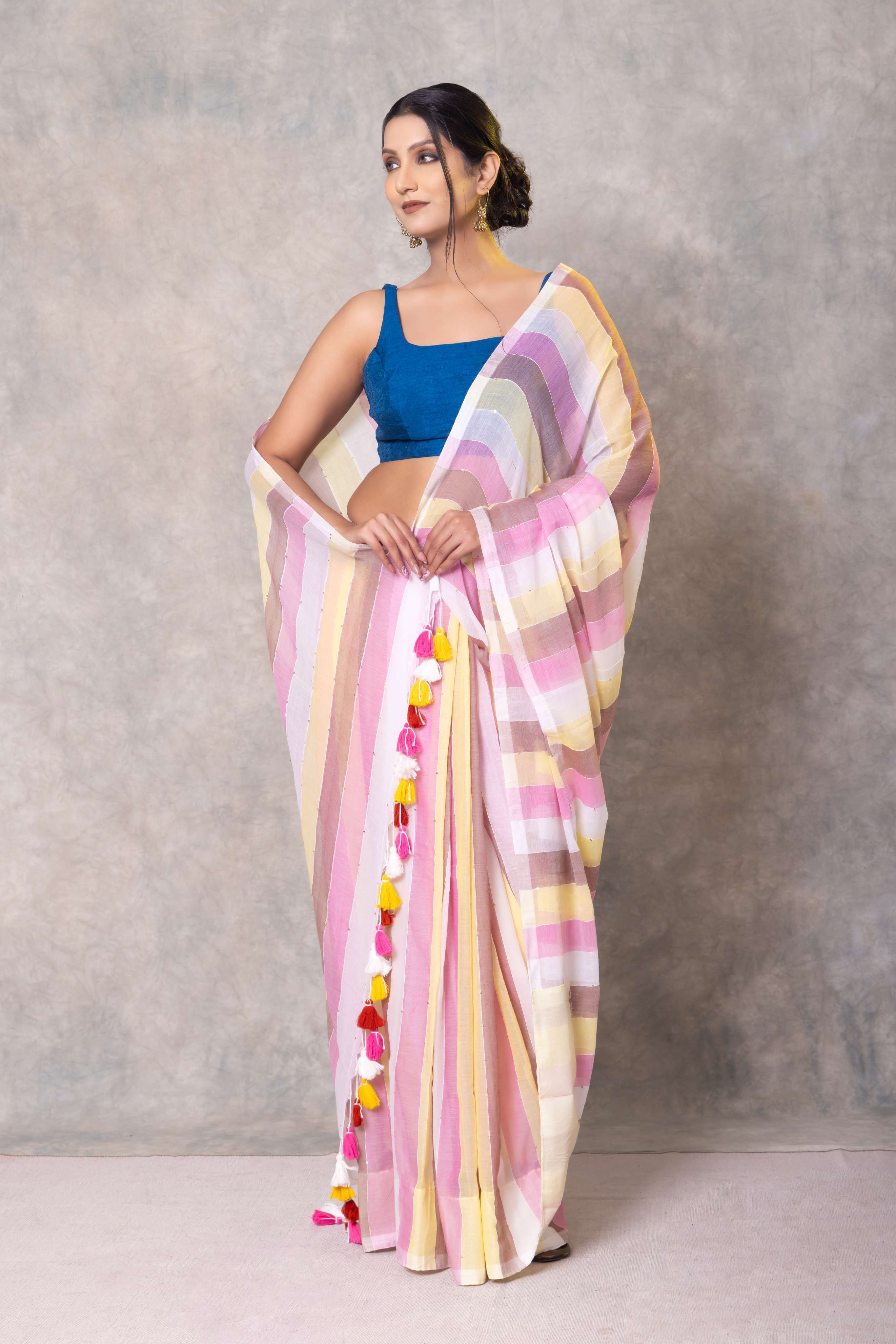Woman wearing a colorful saree with a blue blouse against a gray background