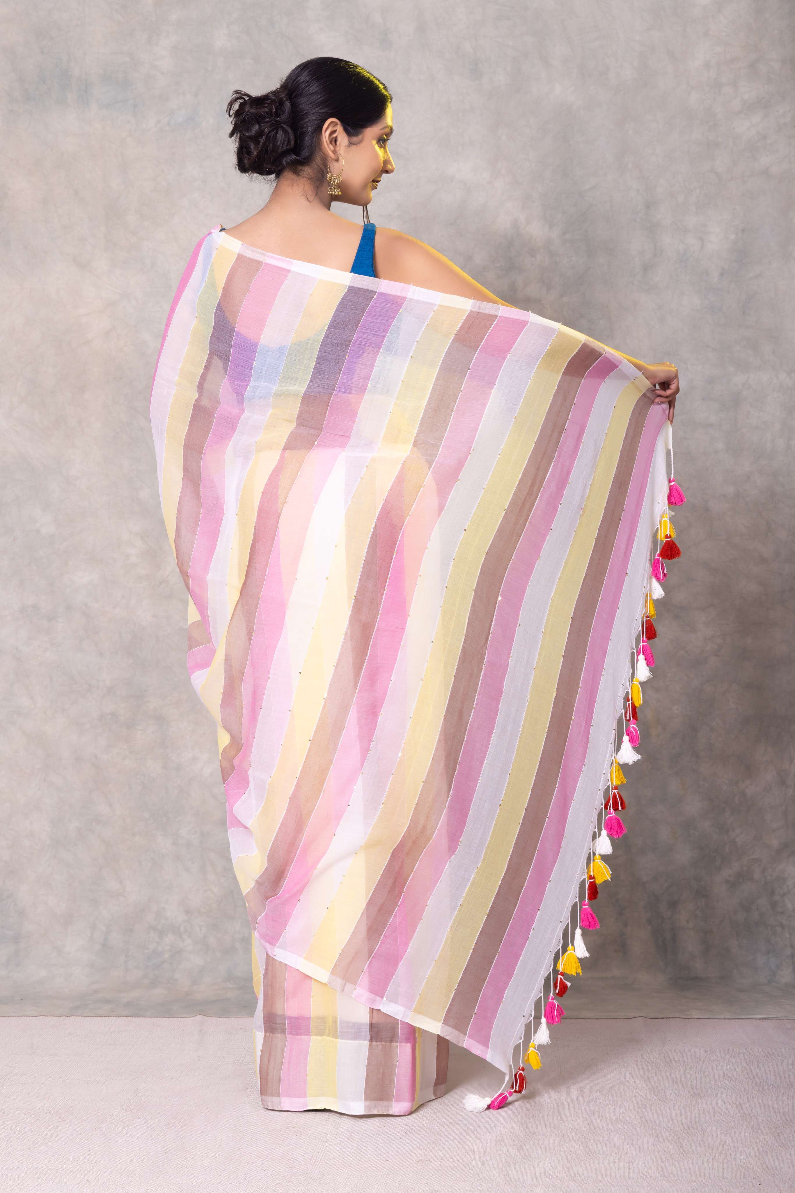 Woman holding a multicolored striped saree with tassels against a gray background