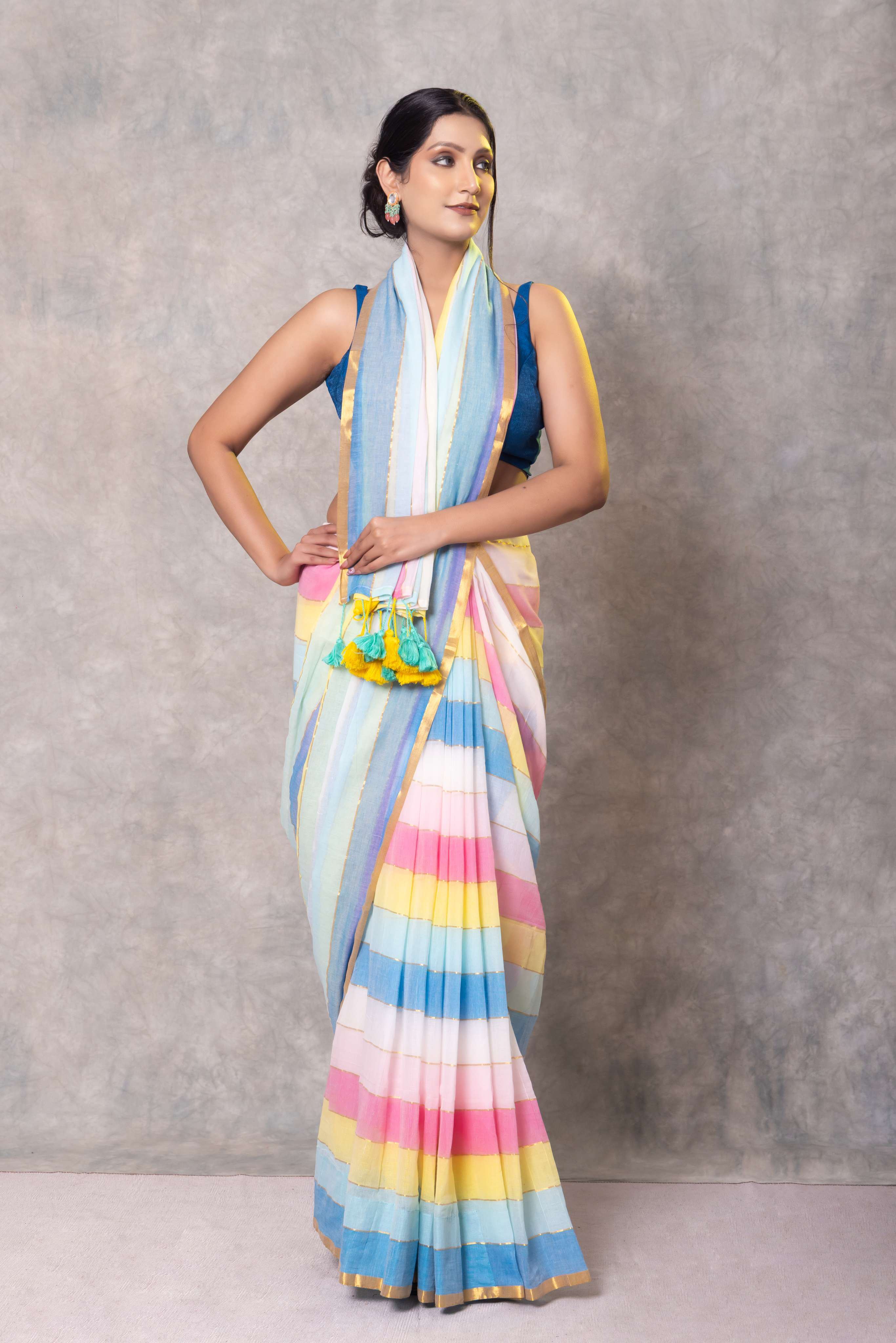 Woman wearing a colorful striped saree against a plain background