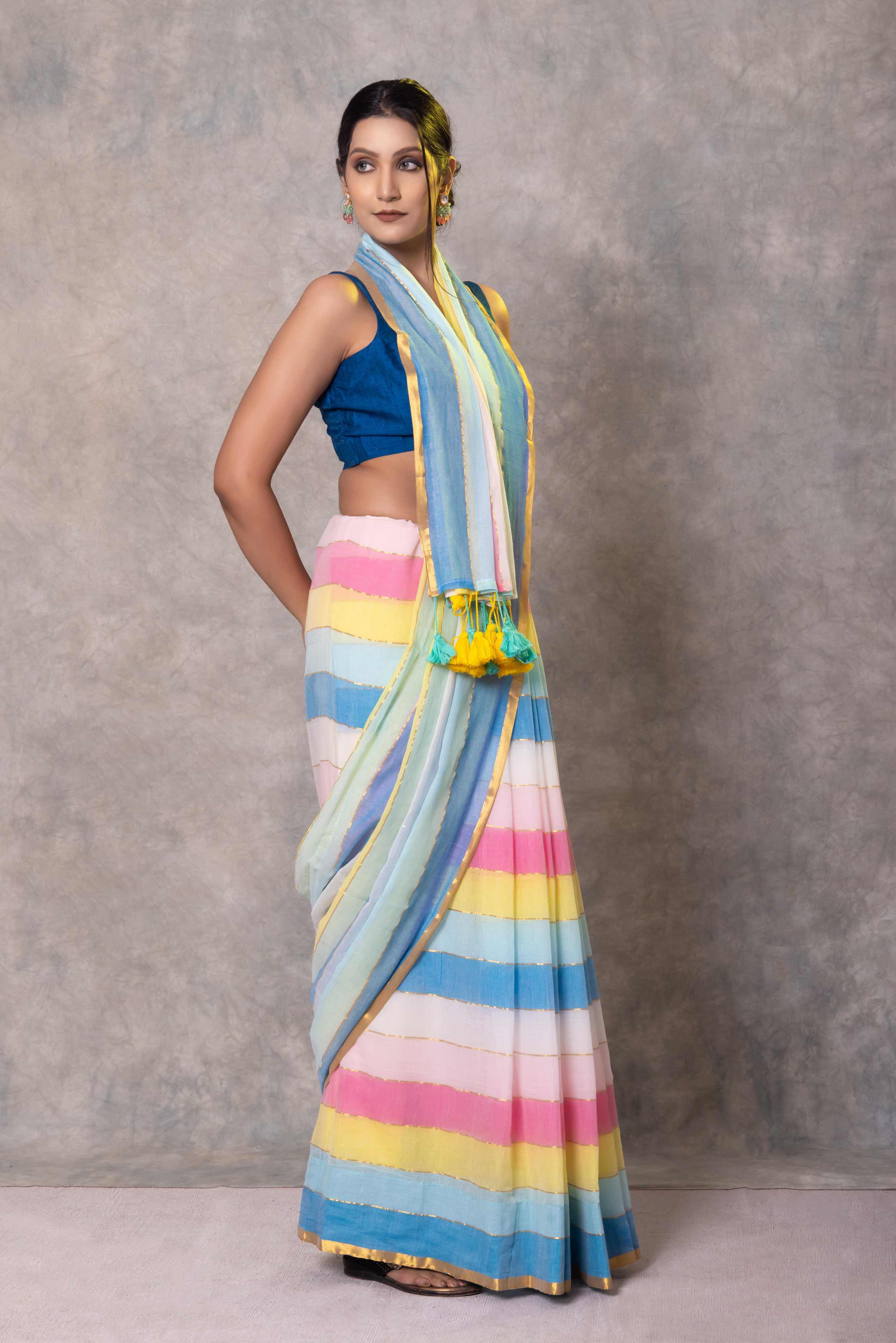 Woman wearing a colorful striped saree with a blue blouse against a gray background