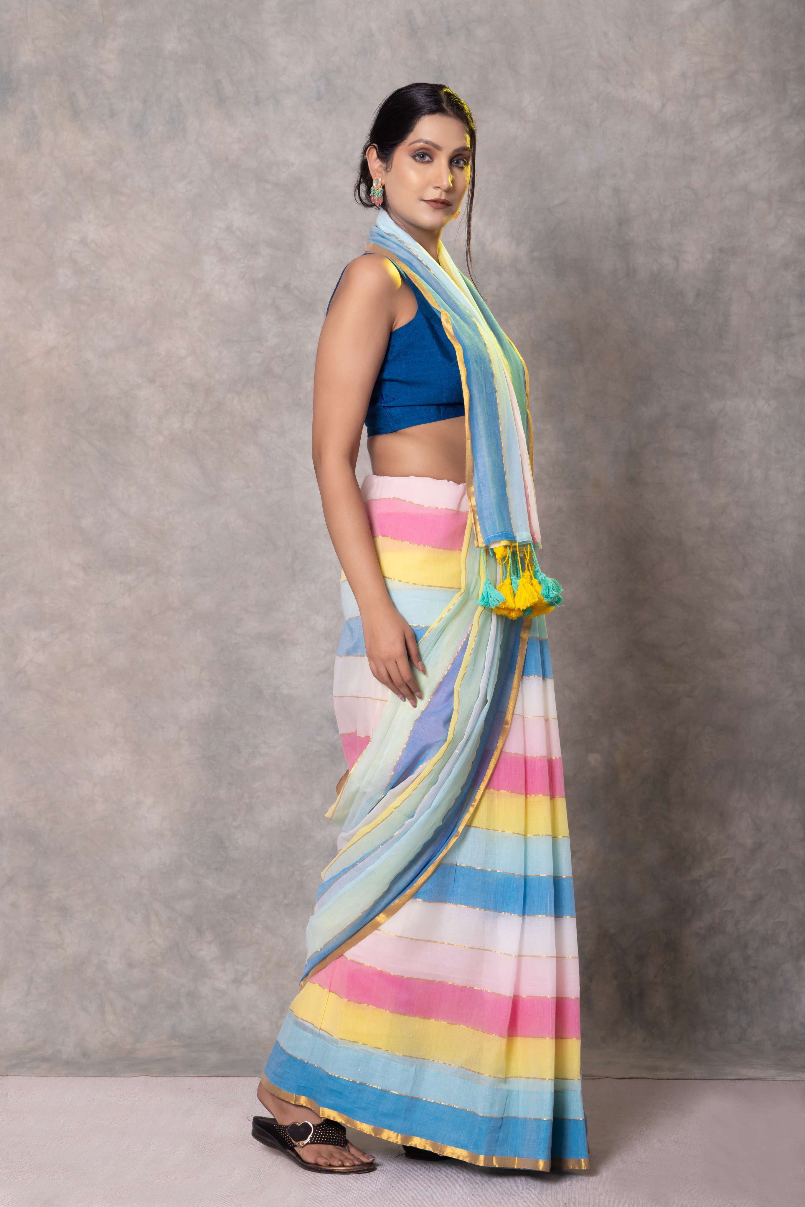 Woman wearing a colorful striped saree with a blue blouse against a gray background