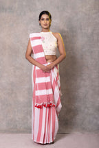 Woman wearing a pink and white saree with a plain background
