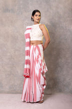Woman wearing a pink and white striped saree with a plain background
