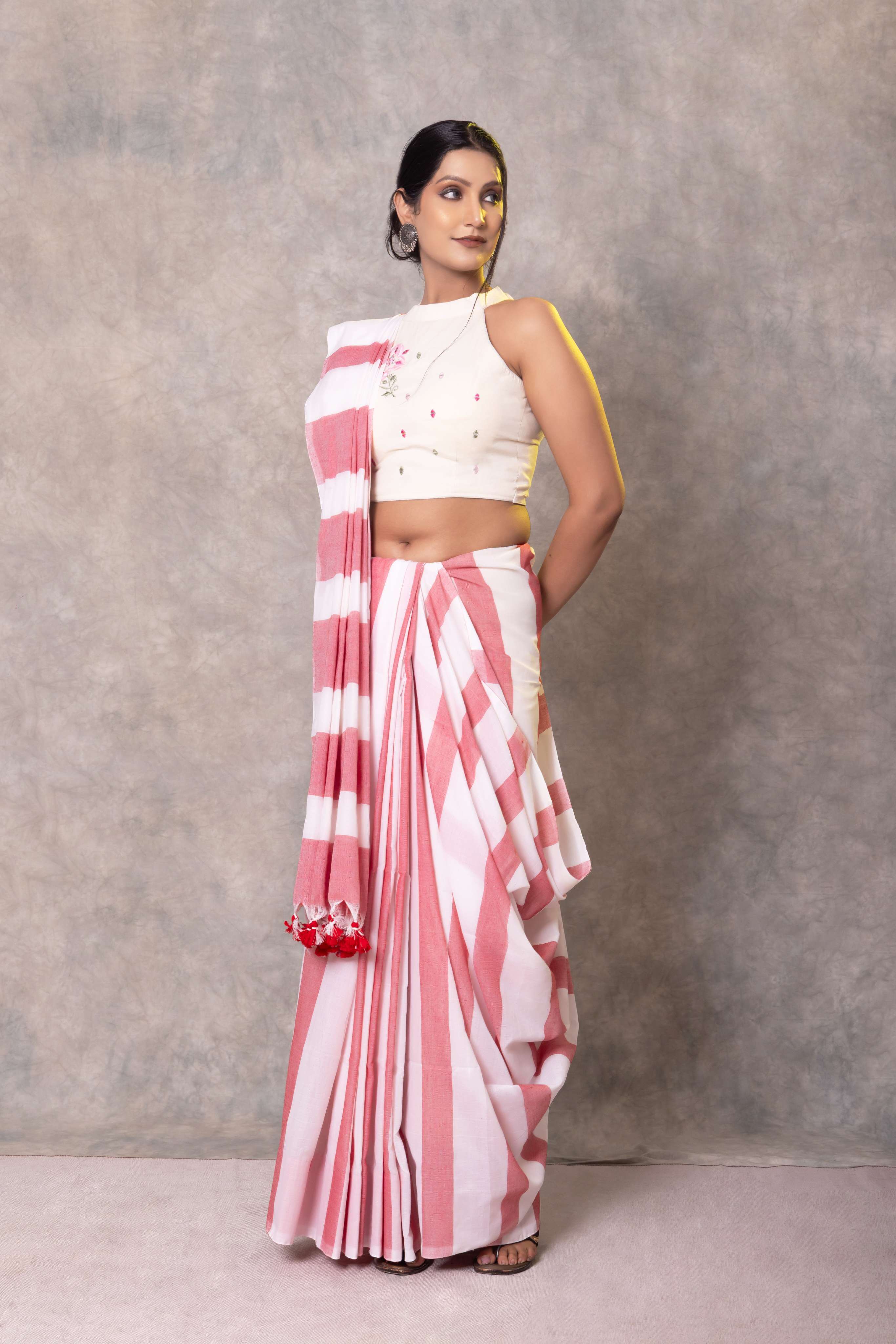 Woman wearing a pink and white striped saree with a plain background