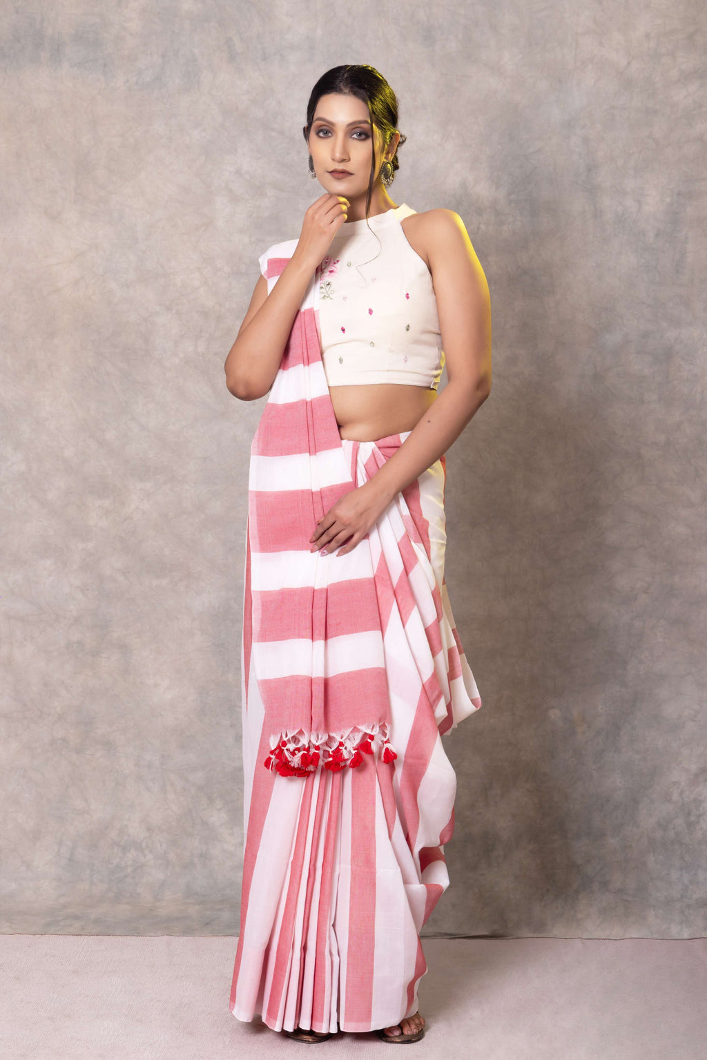 Woman wearing a white and pink striped saree with a plain background