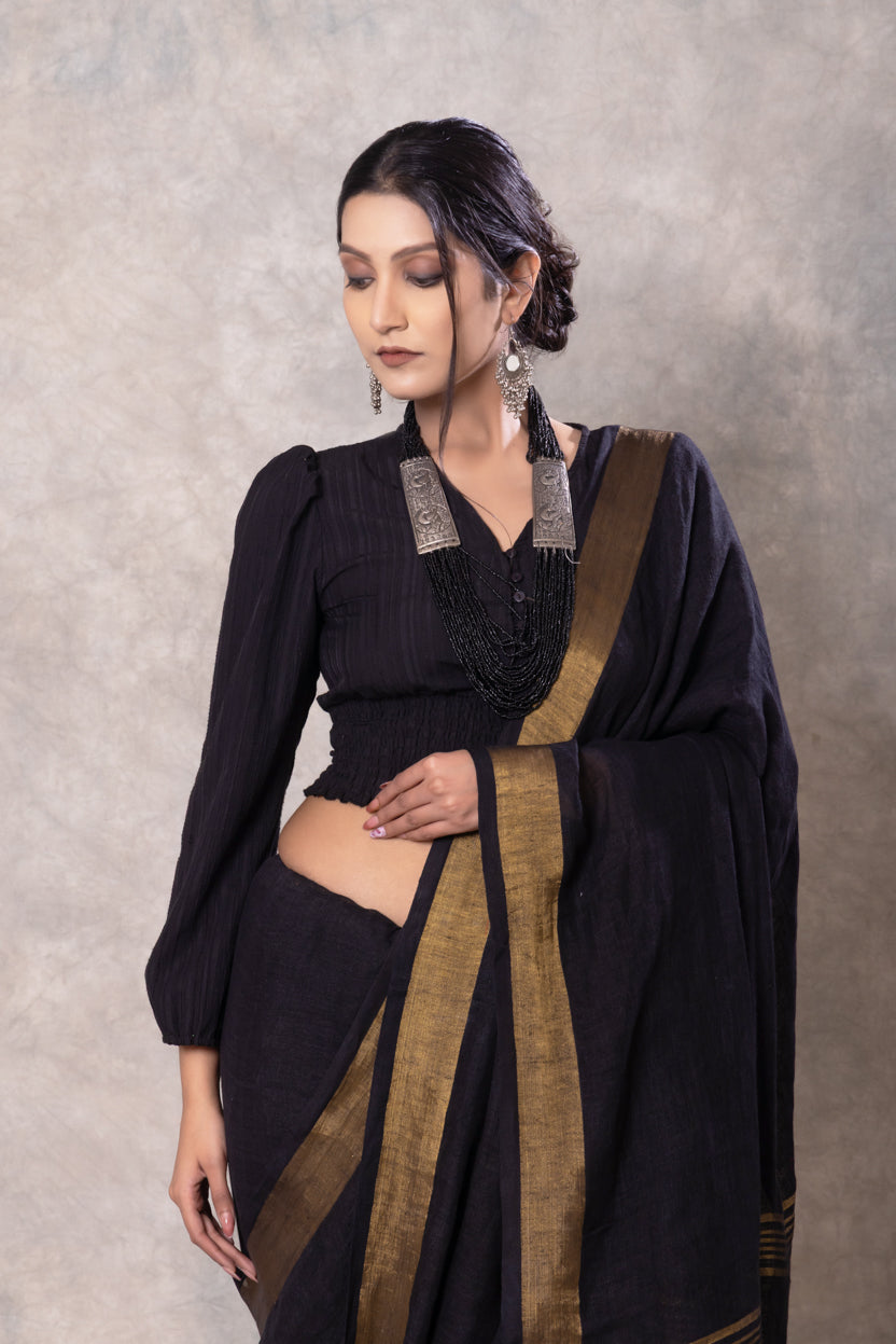 Woman wearing a black and gold traditional outfit against a neutral background