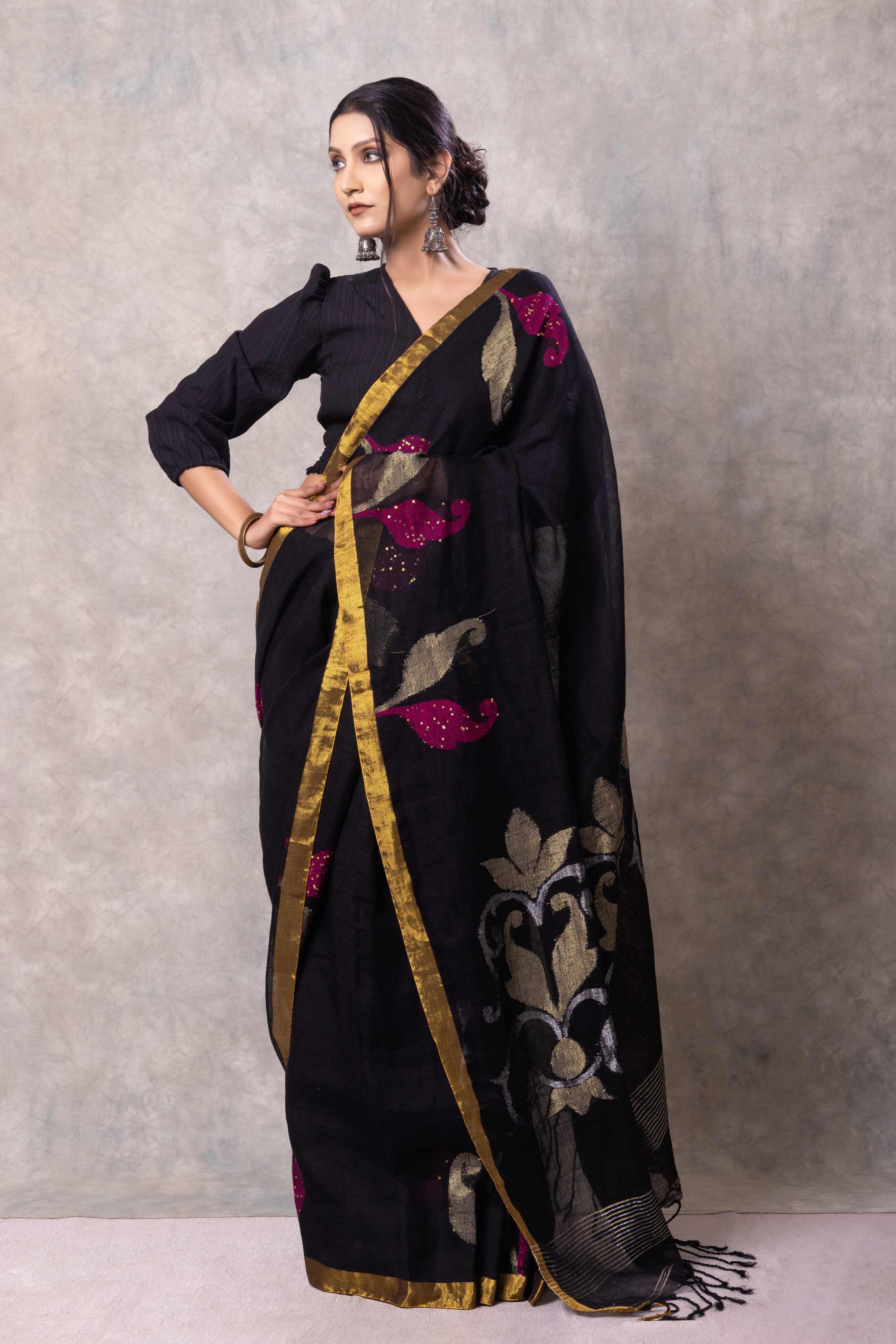 Woman wearing a black saree with floral patterns on a gray background