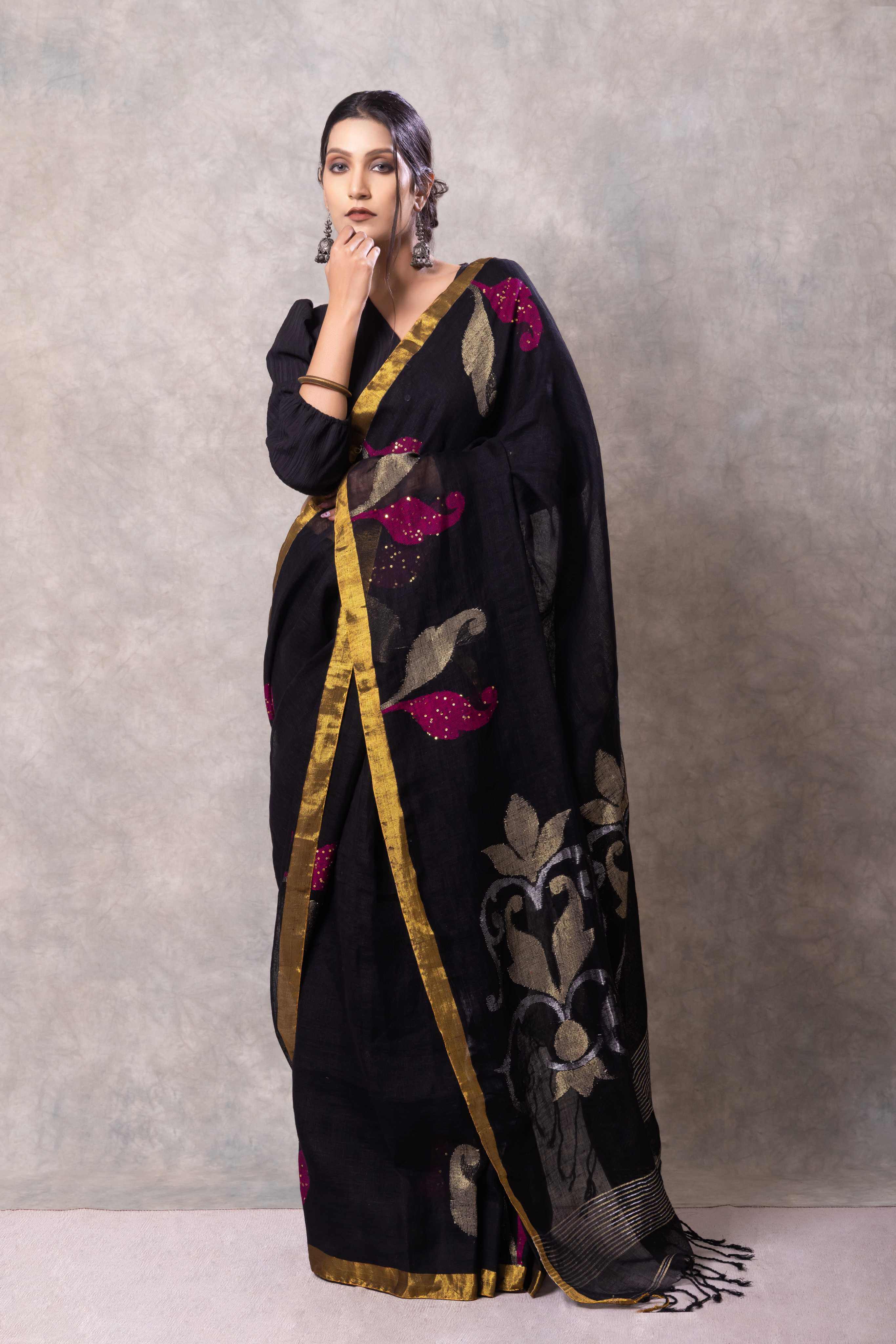 Woman wearing a black saree with floral patterns on a gray background