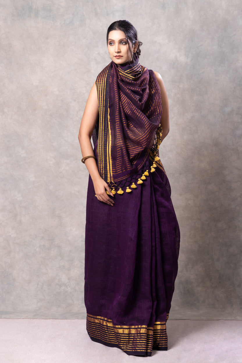 Woman wearing a purple saree with a matching shawl against a gray background