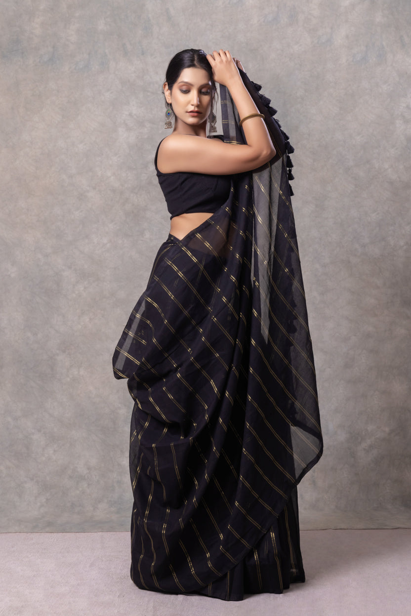 Woman wearing a black saree with a plain background