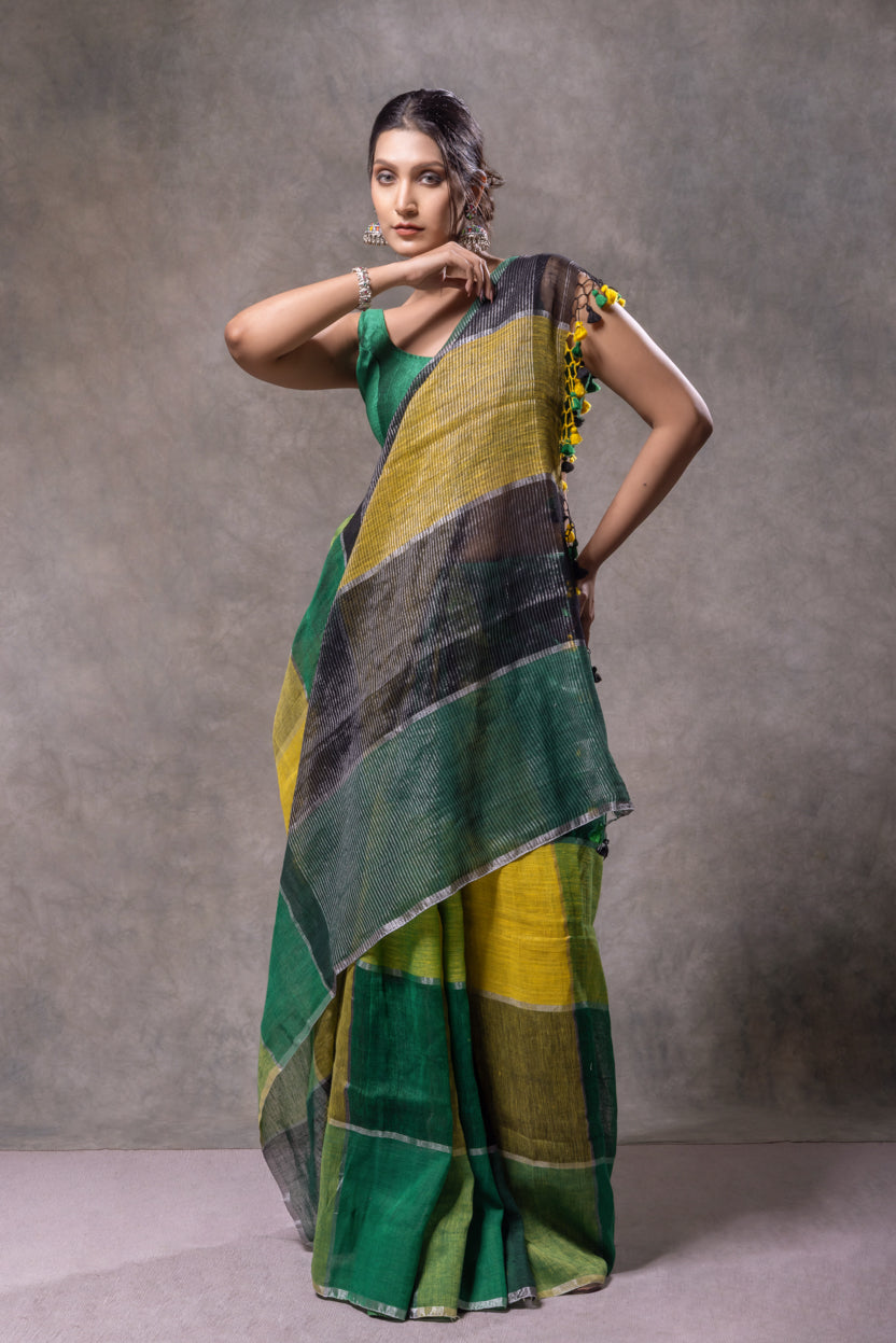 Woman wearing a green and yellow saree against a gray background