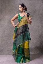 Woman wearing a green and yellow saree against a gray background