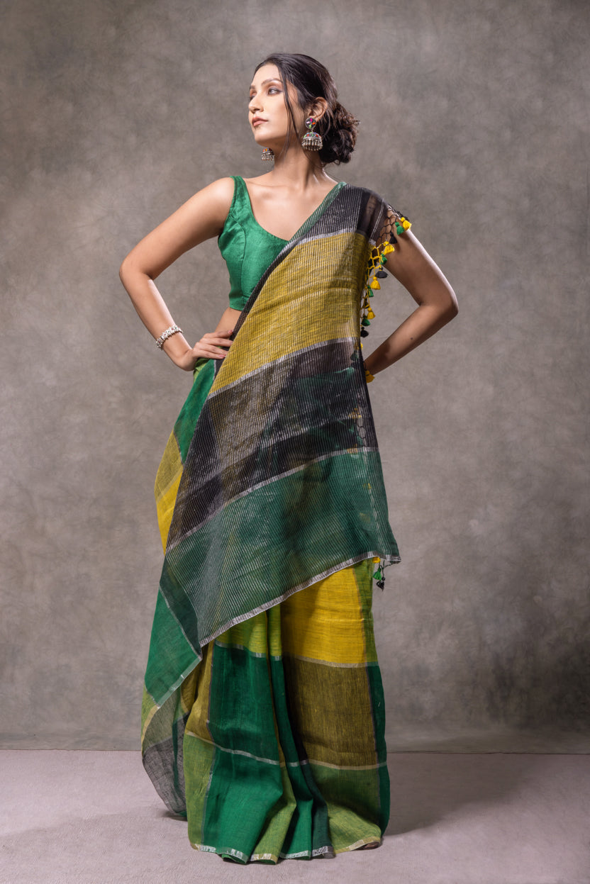 Woman wearing a green and yellow saree against a gray background