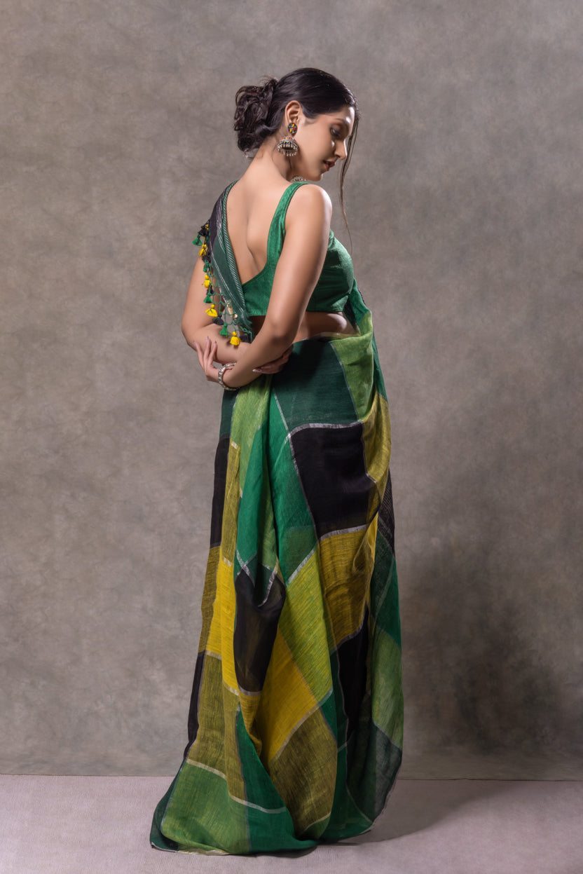 Woman wearing a green and yellow patterned saree against a gray background