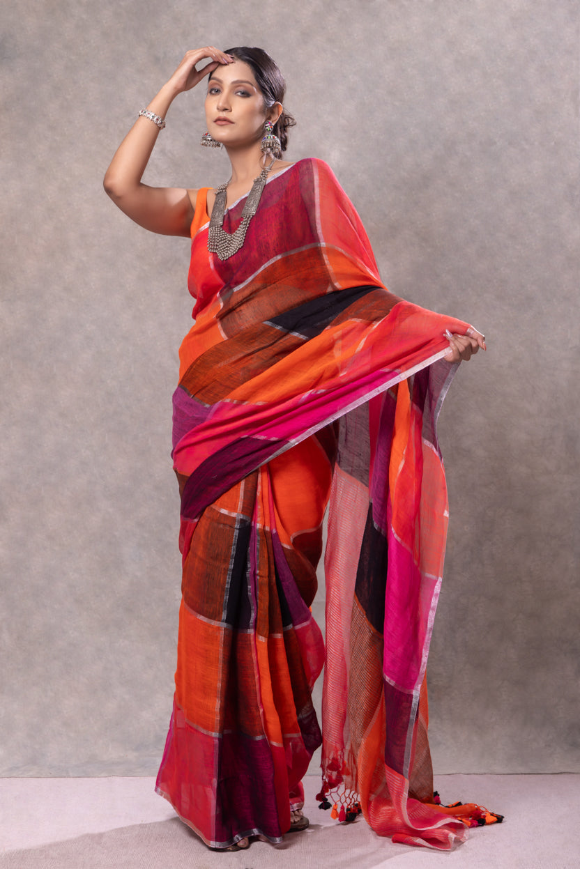 Woman wearing a vibrant red and orange saree with a plain background