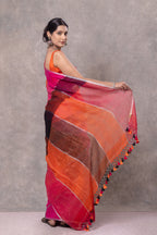 Woman holding a colorful saree with a gradient of red, orange, and pink against a gray background