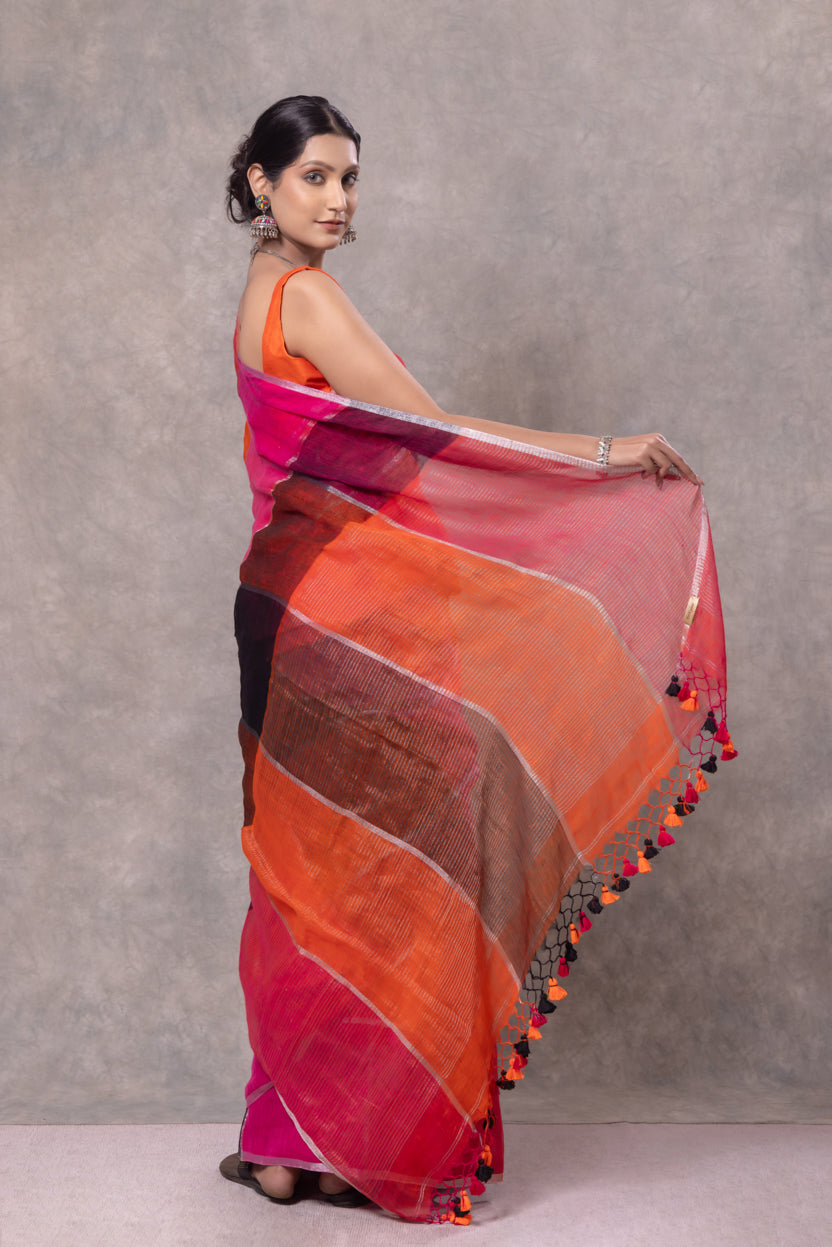 Woman holding a colorful saree with a gradient of red, orange, and pink against a gray background