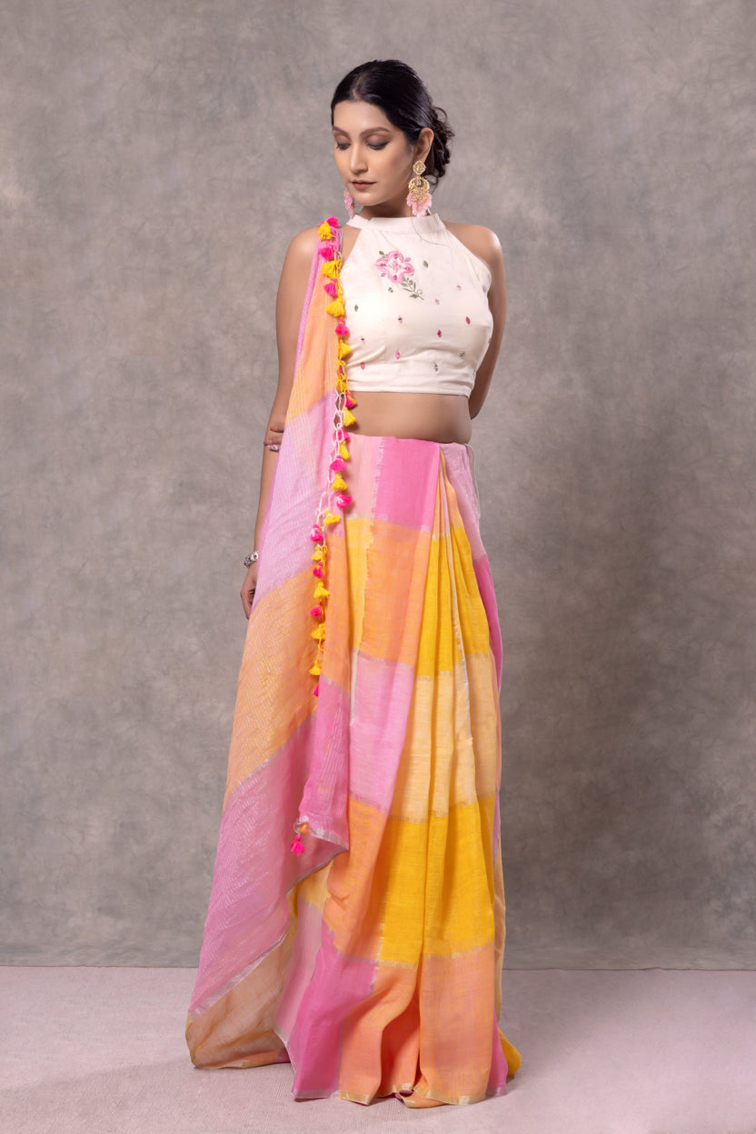 Woman wearing a colorful saree with a white blouse against a gray background