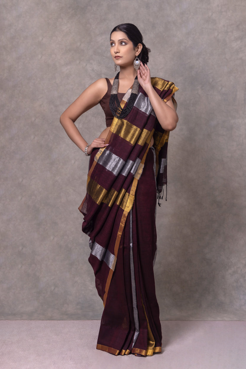 Woman wearing a striped saree against a plain background