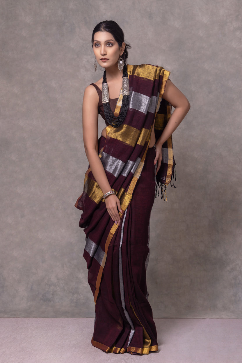 Woman wearing a traditional saree with a patterned design against a gray background