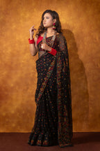 Woman wearing a black saree with red accents against an orange background