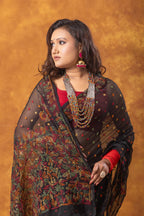 Woman wearing a traditional saree with intricate patterns against an orange background