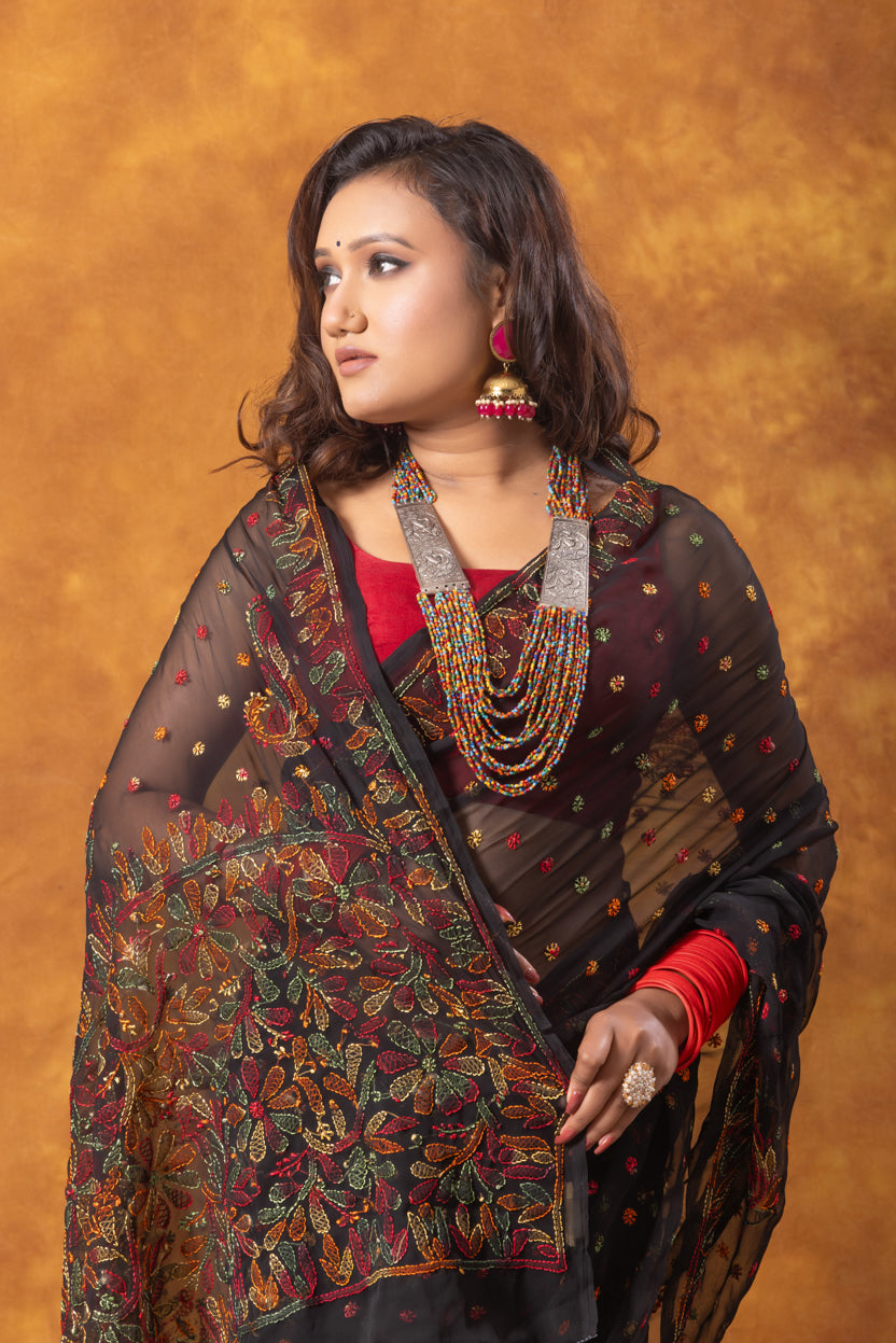 Woman wearing a traditional saree with intricate patterns against an orange background