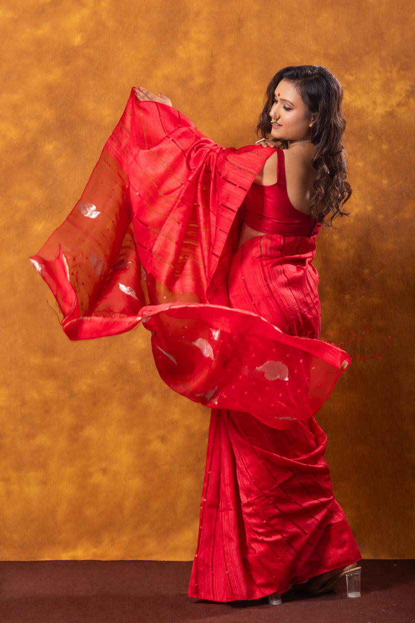 Woman in a red saree with a floral pattern against an orange background