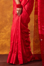 Red saree with a person holding it against an orange background
