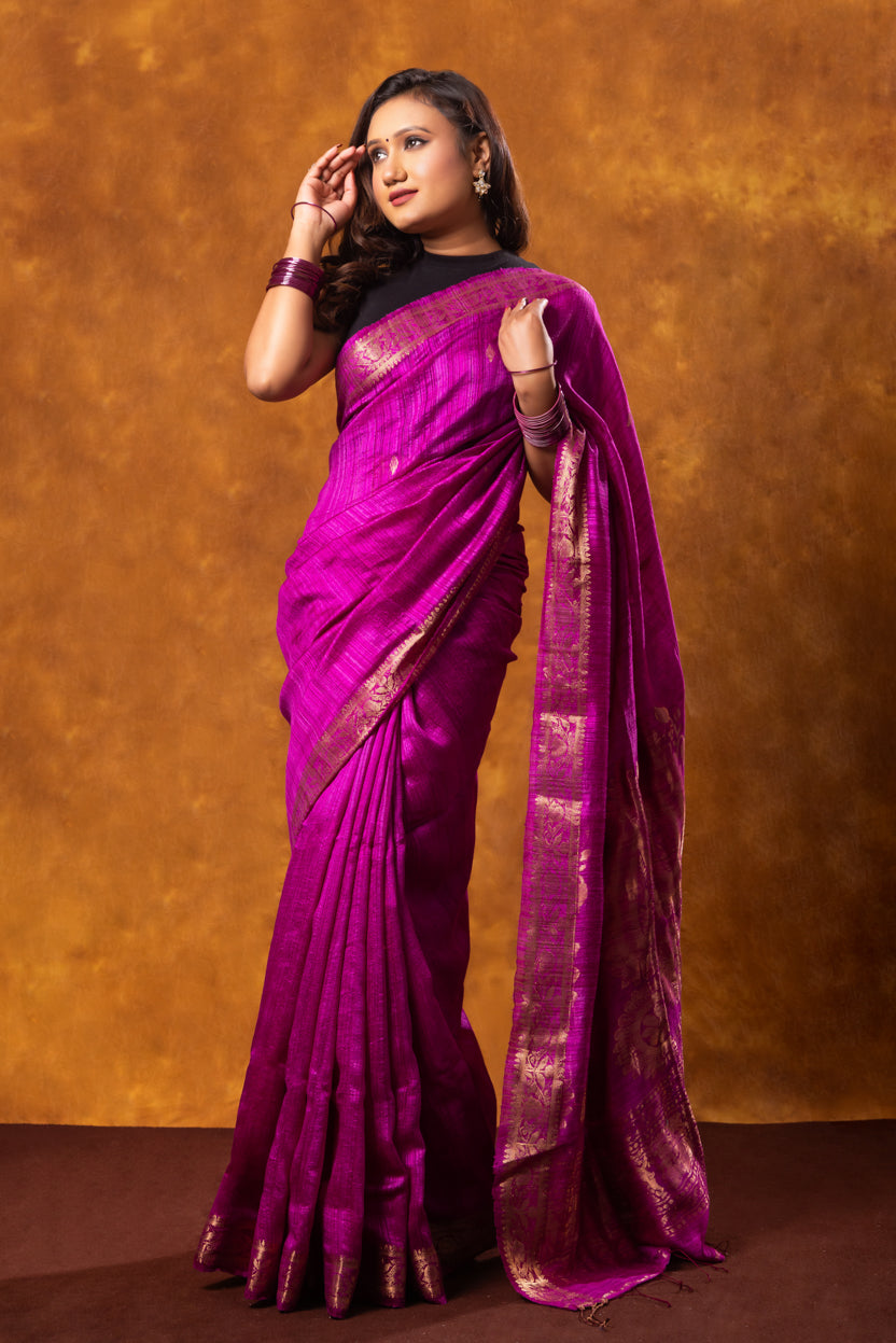 Woman wearing a vibrant purple saree against a warm brown background