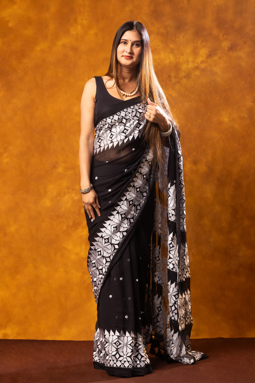 Woman wearing a black and white saree with a brown background