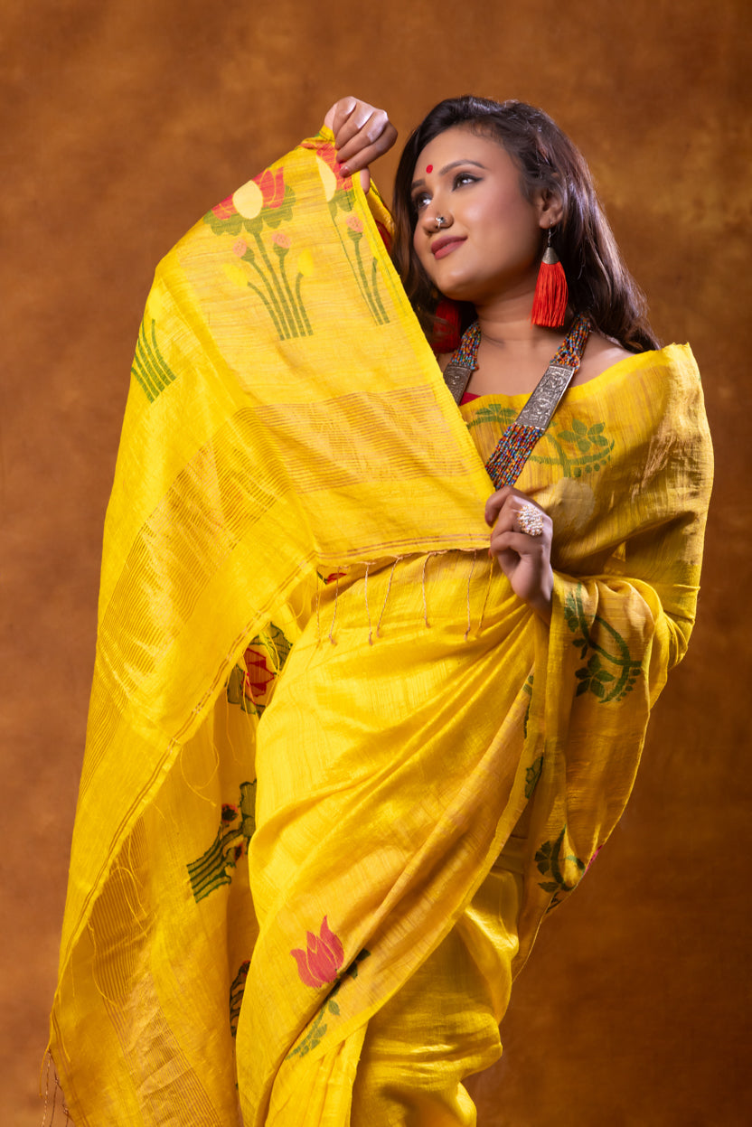 Woman in a yellow saree with floral patterns against a brown background