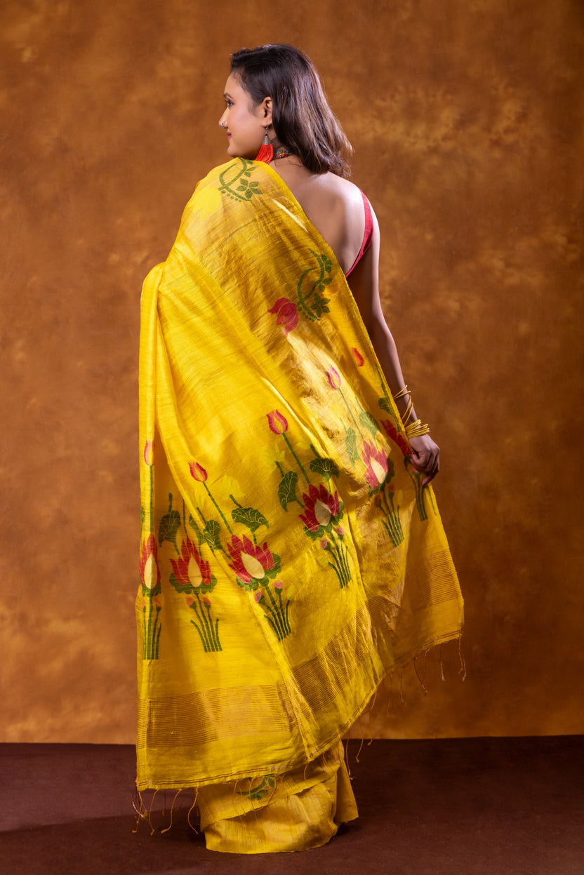 Woman wearing a yellow saree with floral patterns on a brown background