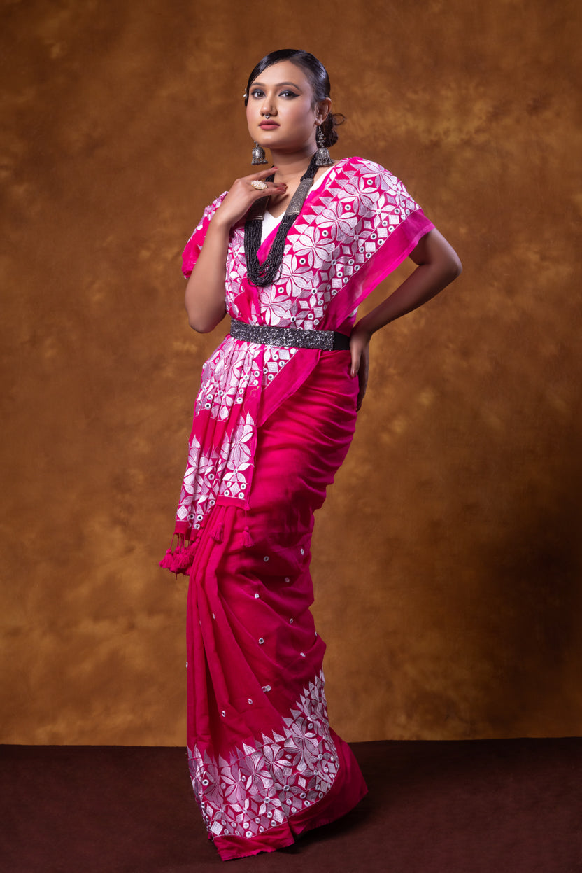 Woman wearing a pink and white saree with a brown background