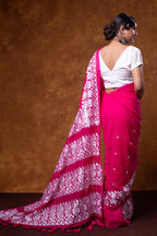 Woman wearing a pink saree with white patterns against a brown background