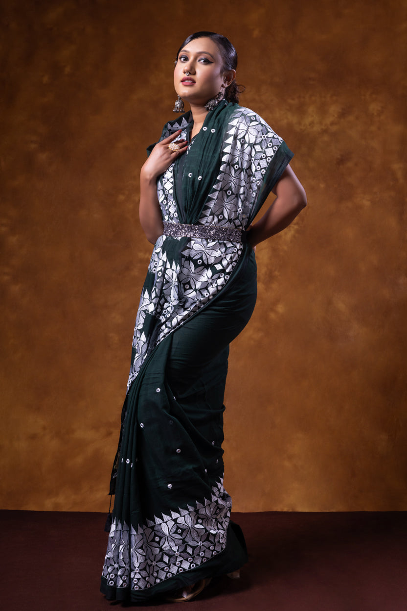 Woman wearing a black and white patterned saree against a brown background