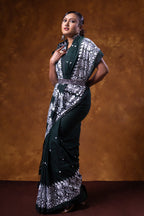 Woman wearing a black and white patterned saree against a brown background