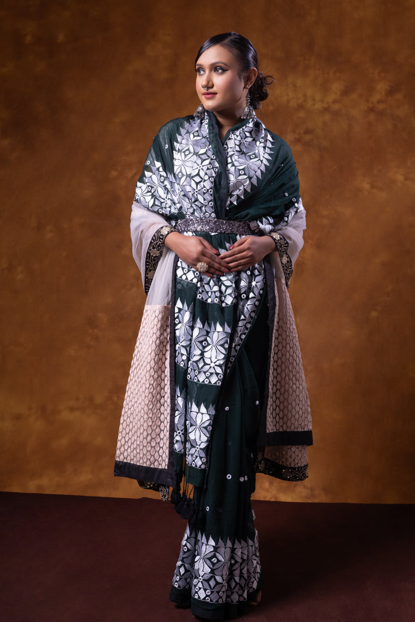 Woman wearing a traditional outfit with a patterned shawl against a brown background