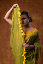 Woman holding a green saree with yellow tassels against a brown background
