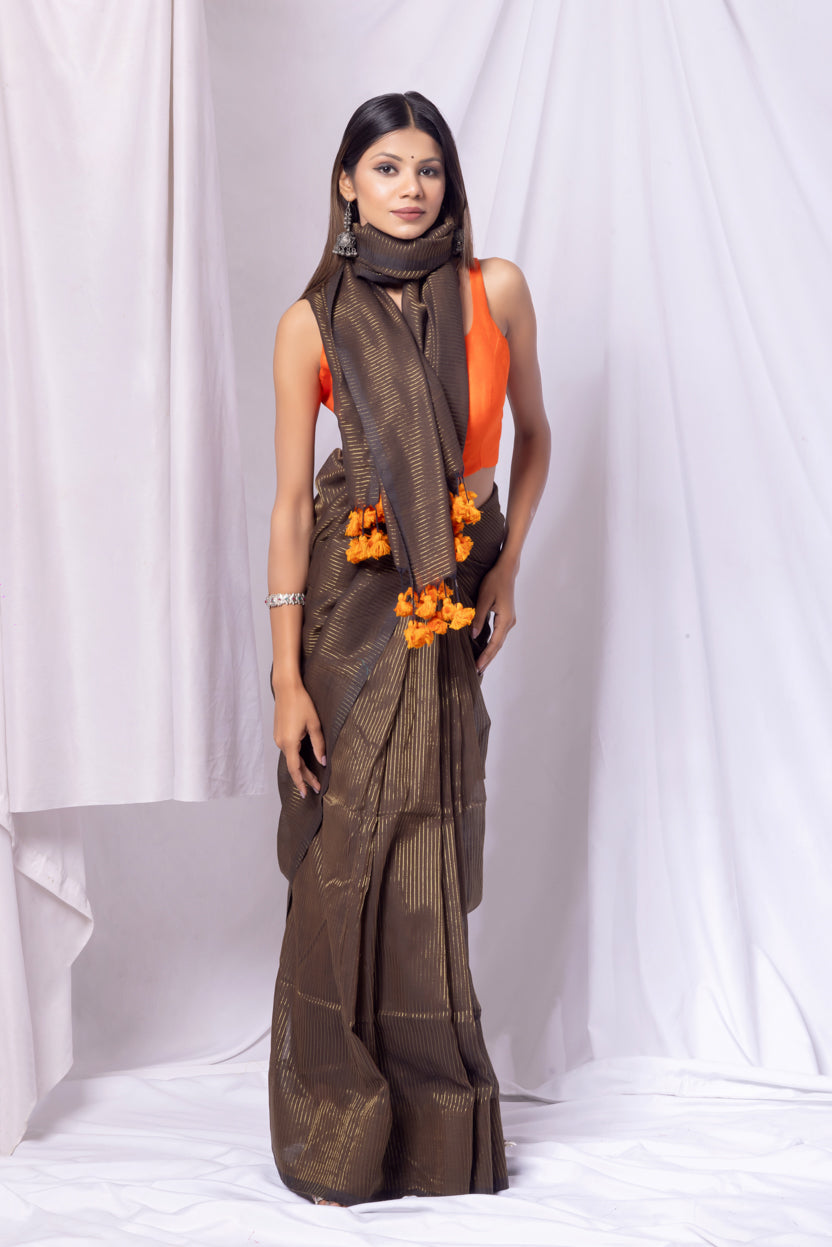 Woman wearing a brown saree with orange blouse against a white background