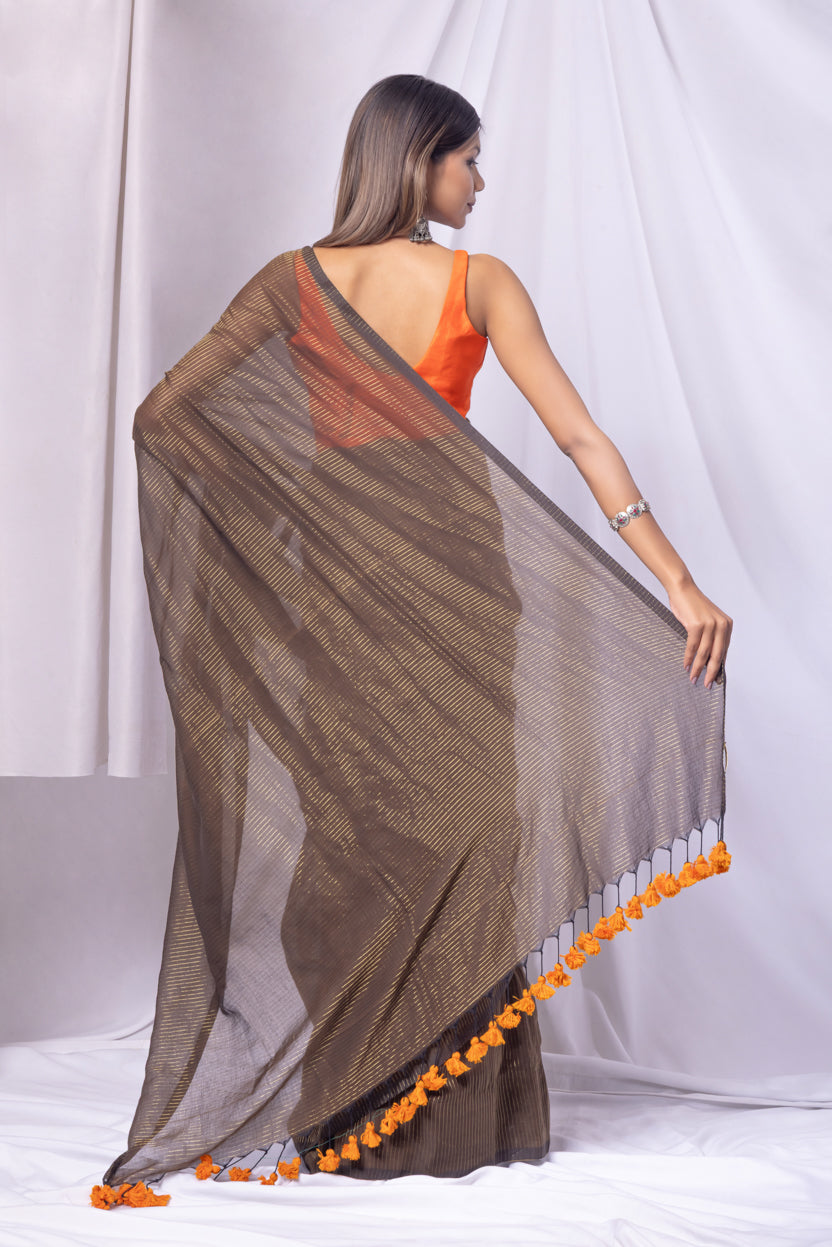Woman wearing a brown saree with orange accents on a white background