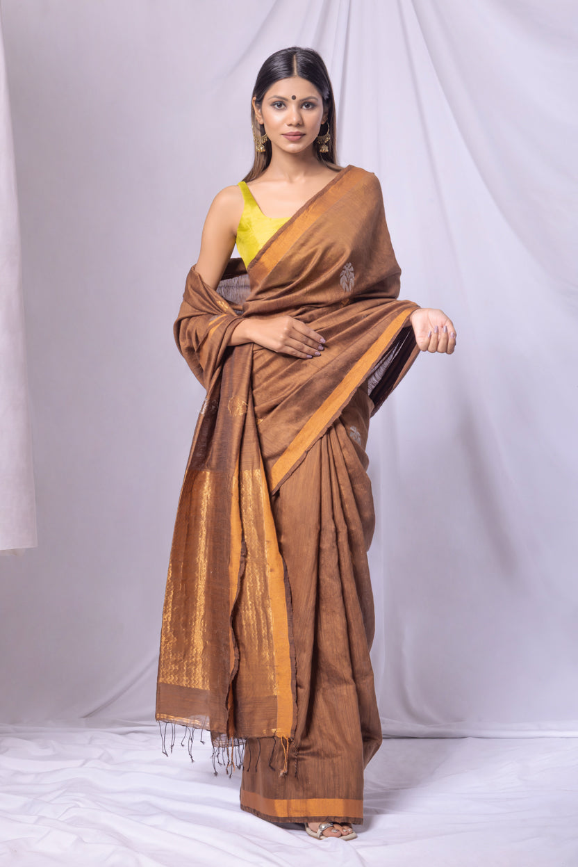 Woman wearing a brown saree with a yellow blouse against a white background