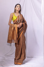 Woman wearing a brown saree with a yellow blouse against a white background