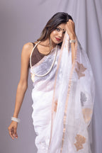 Woman wearing a white saree with a star pattern against a gray background