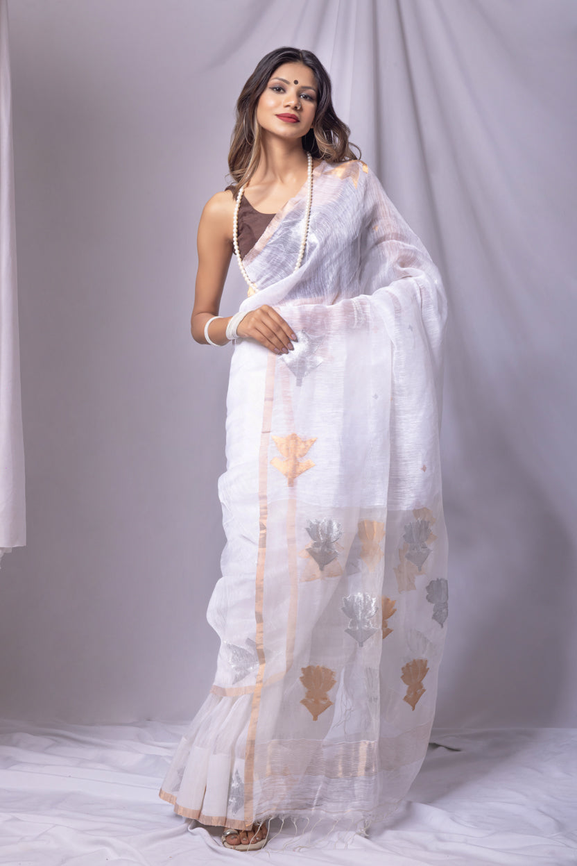 Woman wearing a white saree with floral patterns on a plain background