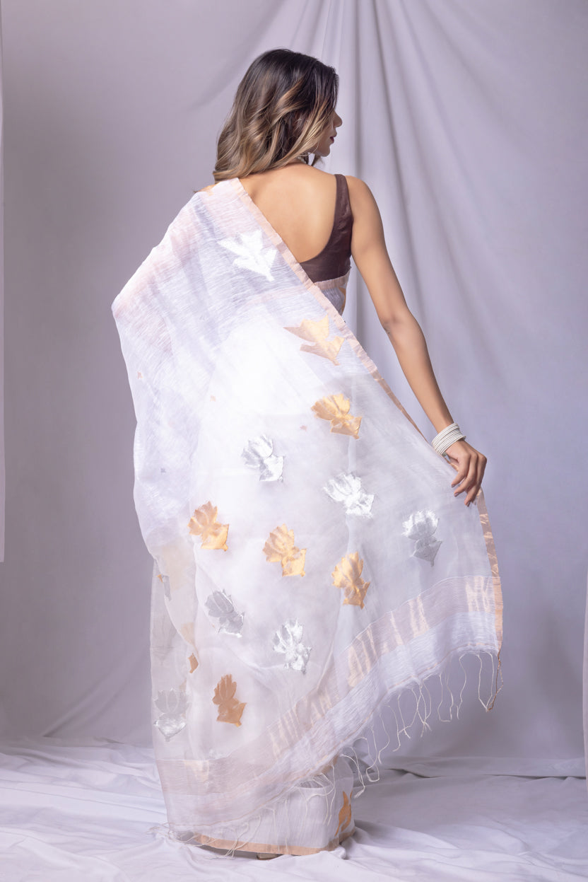 Woman wearing a white saree with floral patterns on a plain background